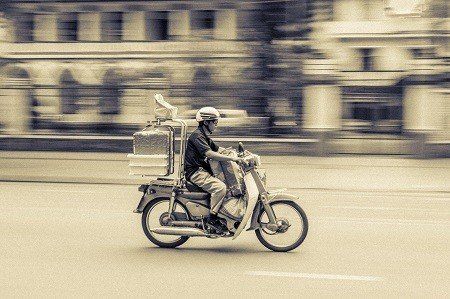 A man is riding a motorcycle down a street.